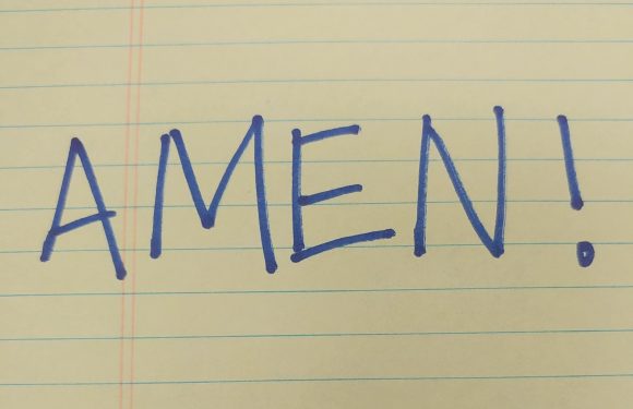 Handwritten on lined yellow paper, the word "AMEN!" is written in blue ink with capital letters and an exclamation mark.