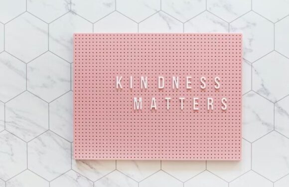 Pink letter board with white letters spelling "KINDNESS MATTERS" on a white marble and hexagonal tile surface.