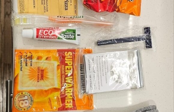 Assorted snack foods, toothbrush, pen, zippered plastic bag, thermal socks, and a small black pouch on a white surface.