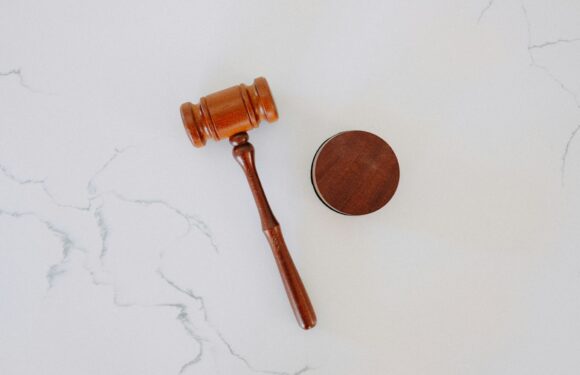 A wooden gavel and sound block placed on a white marble surface.
