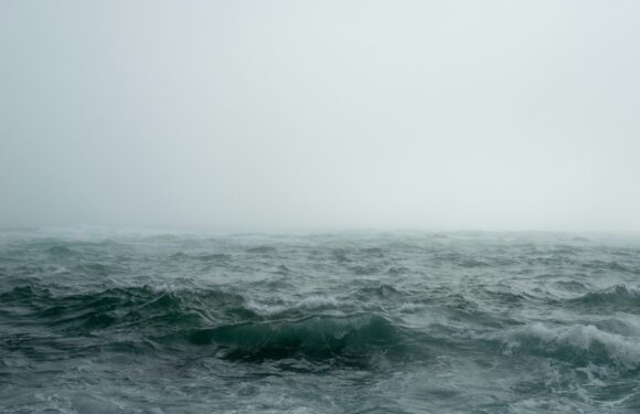 Rough ocean waves under a cloudy, foggy sky, with no land or boats visible.