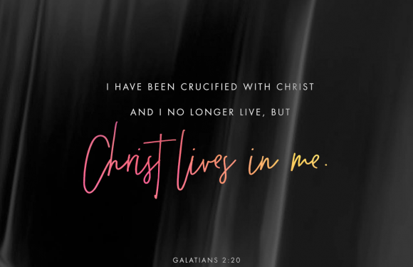 Black and gray swirling background with white, pink, orange, and yellow text that reads: "I have been crucified with Christ and I no longer live, but Christ lives in me. Galatians 2:20."