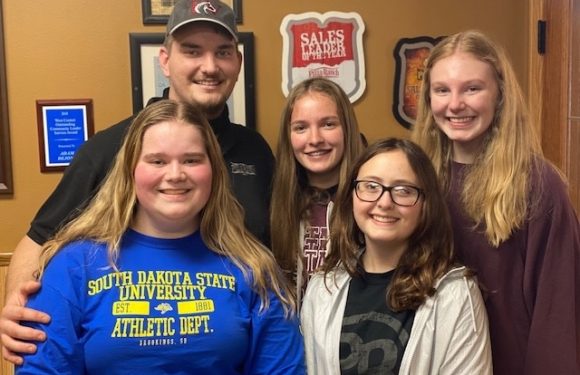 Group of five smiling young women and one man posing inside a restaurant, with "Sales Maker of the Year" sign and Pizza Ranch logos on the wall behind them.