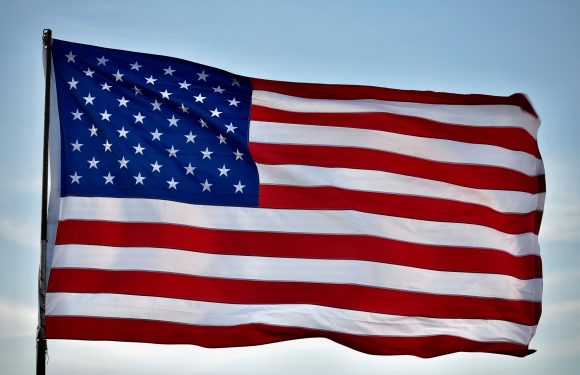 American flag waving outdoors against a cloudy sky.