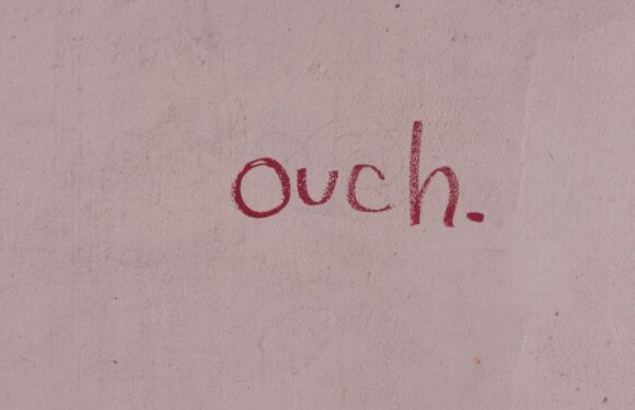 The wall has a pinkish tone with the handwritten word "ouch." in red ink.