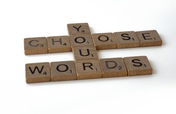 Scrabble tiles spelling out "CHOOSE YOUR WORDS" on a white background.