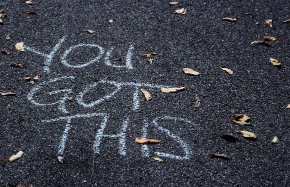 "Yard and chalk message on asphalt: 'You got this' with scattered fallen leaves."