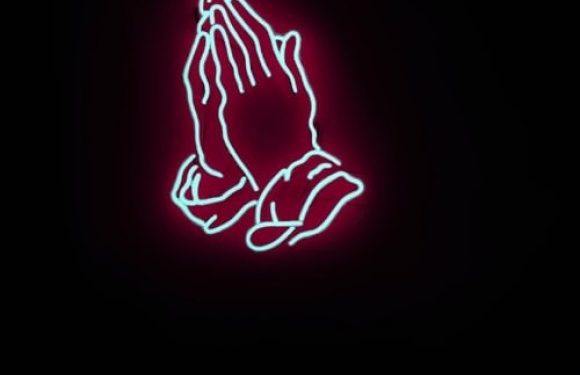 A neon sign of praying hands outlined in blue with a pink glow on a black background.