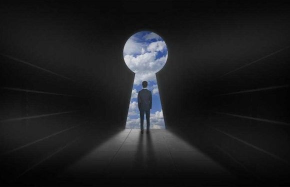 A person in a suit stands in a dark corridor, looking at a keyhole-shaped opening revealing a bright sky with clouds, symbolizing opportunity or discovery.