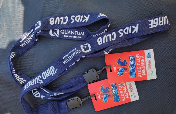 Blue lanyard with "KIDS CLUB" and "QUANTUM CREDIT UNION" printed on it, attached to red and white event badges for the 2022 Windsor Kids Club Member event, with a black plastic clip.