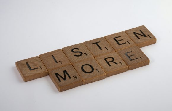 The image shows wooden letter tiles arranged to spell "LISTEN" and "MORE" on a plain white background.