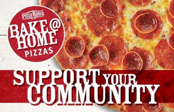 A close-up of a pepperoni pizza with melted cheese, alongside a red and white sign reading "Pizza Ranch Bake@Home Pizzas" and "Support Your Community."