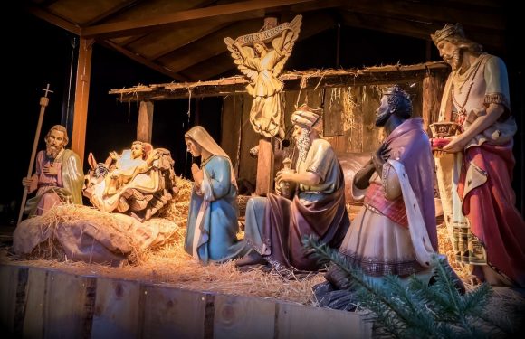 A nativity scene display with figures of Jesus, Mary, Joseph, the Wise Men, and angels, set against a wooden stable background.