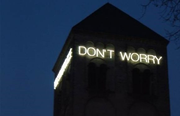 A dark tower with the illuminated words "DON'T WORRY" on its upper part against a night sky.