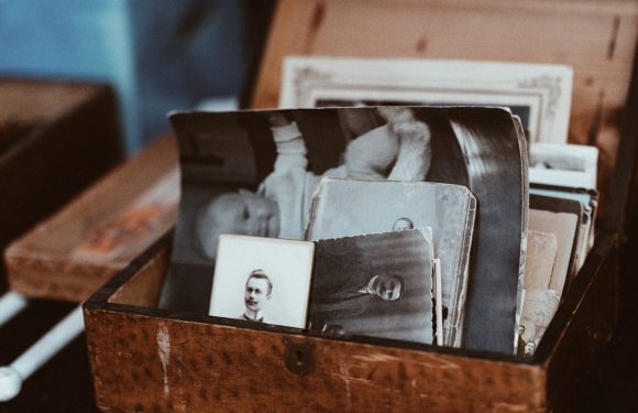 A wooden box filled with black-and-white photographs of people, some older and some more recent.