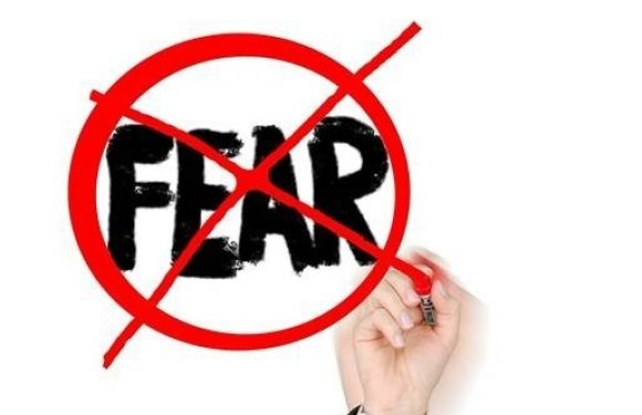 Hand holding a marker draws a red circle and slash over the word "FEAR," symbolizing the elimination or rejection of fear.