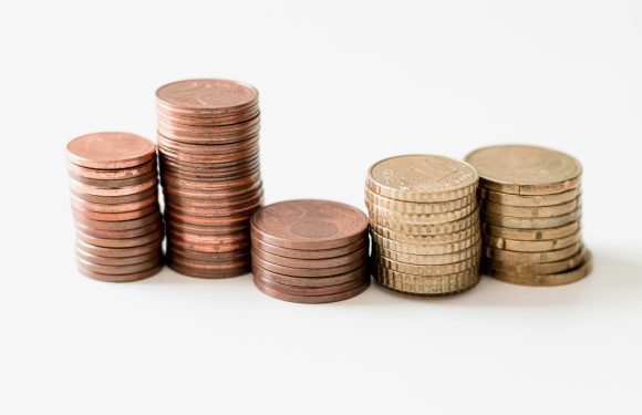Stacks of coins arranged from smallest to largest, with some coins showing signs of wear and tarnish, set against a plain white background.
