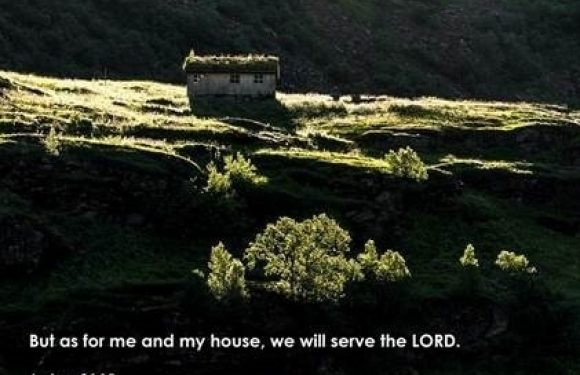 A small house on a hillside surrounded by lush greenery and trees; sunlight highlights the landscape. The text reads: "But as for me and my house, we will serve the LORD. Joshua 24:15."