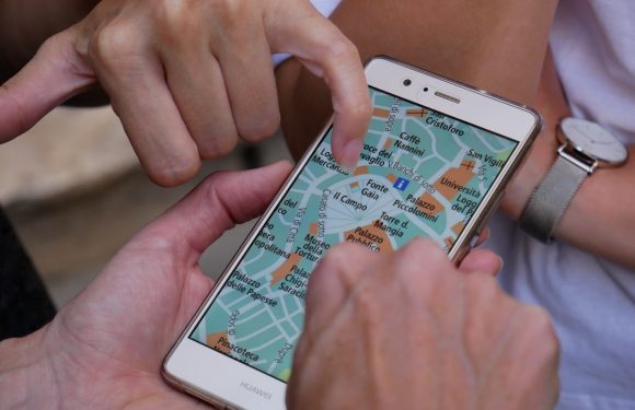 A person with a watch on their wrist is pointing at a map on a Huawei smartphone, showing landmarks such as Palazzo, Piazzette, and other location names.