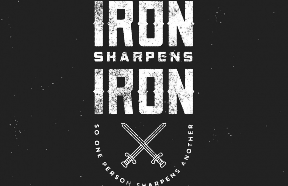 The image features a black background with white distressed text and illustrations. It displays the phrase "As iron sharpens iron, one person sharpens another" from Proverbs 27:17, with two crossed swords below the text.