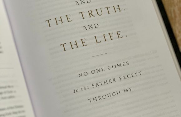 The image shows an open book with a Bible verse on the right page, displaying the text: "I am the way, and the truth, and the life. No one comes to the Father except through me. John 14:6."