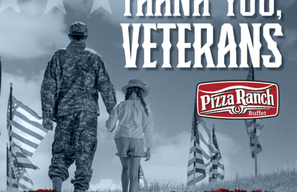 A soldier and a young girl walk together on a grassy field with American flags, with text thanking veterans and promoting a Veterans Day event.