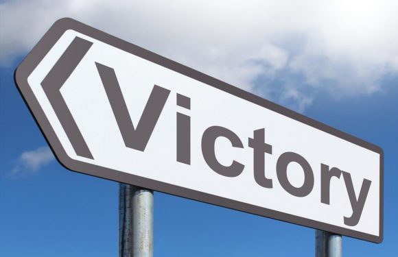 A street sign reading "Victory" against a background of partly cloudy sky.