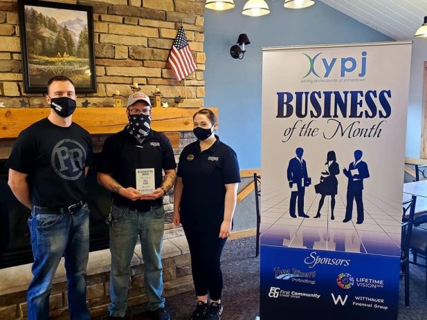 Pizza Ranch owner and managers holding award next to banner naming them Business of the Month winner.