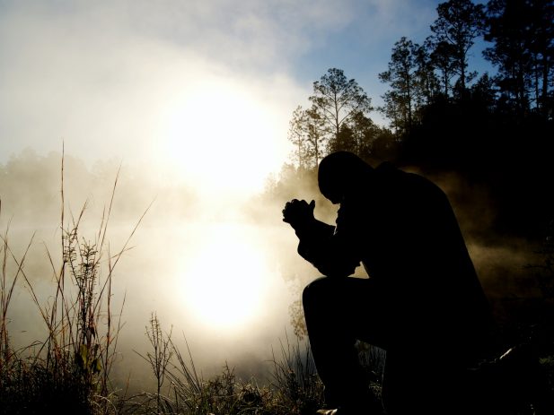 Silhouette man praying in nature