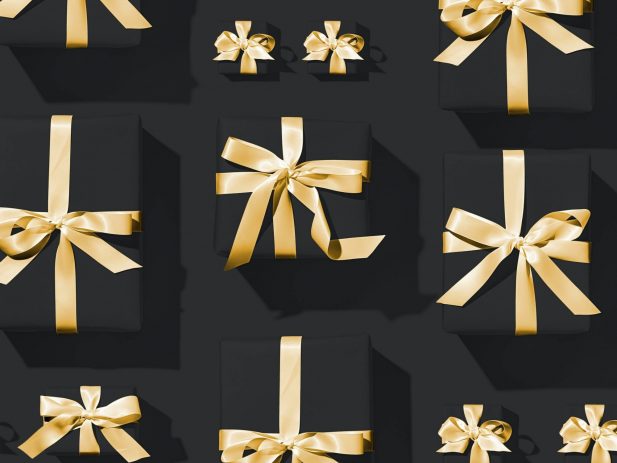 black wrapped gift boxes with gold bows lined in straight rows