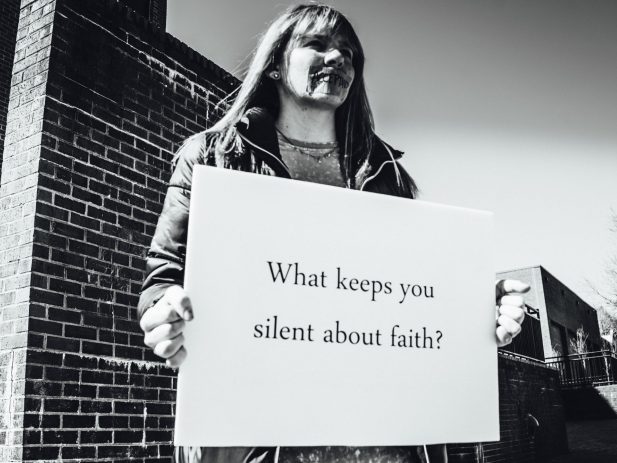 Woman holding sign, "What keeps you silent about faith?"