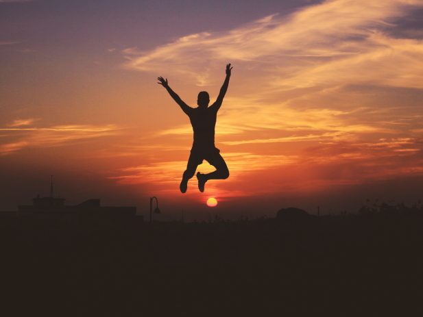 silhouette of a person jumping in front of a sunset background