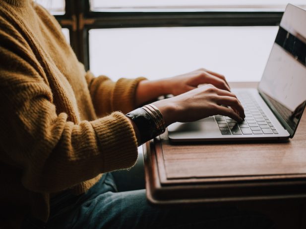 Man sitting at laptop in front of window