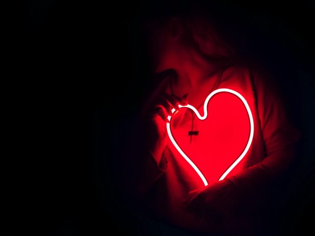 Image of a person holding a glowing heart with a dark background