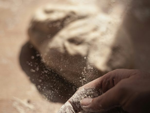 Hand covered in flour making bread.