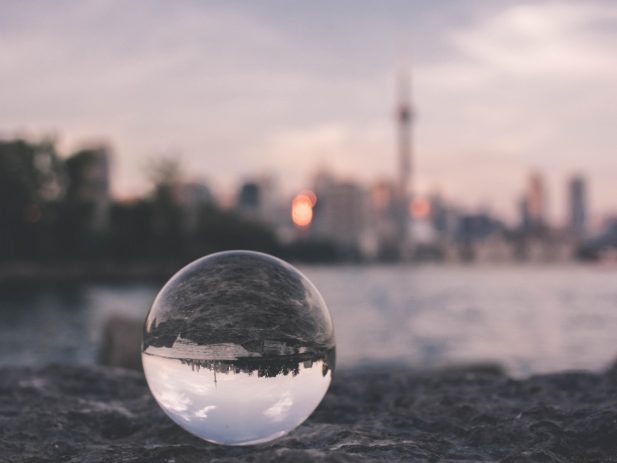 Cityscape in background of glass ball reflecting cityscape upside down.