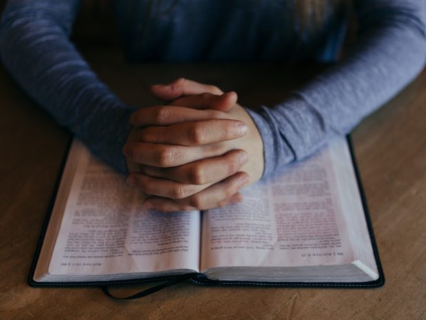 Man praying while laying his hands on the bible