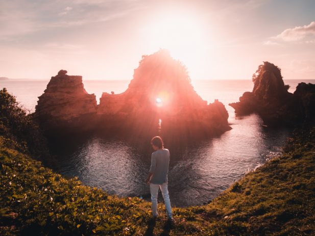 Person standing on the edge of a cliff with a light ahead of her