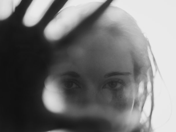 unfocused photo of woman holding hand up to camera lens