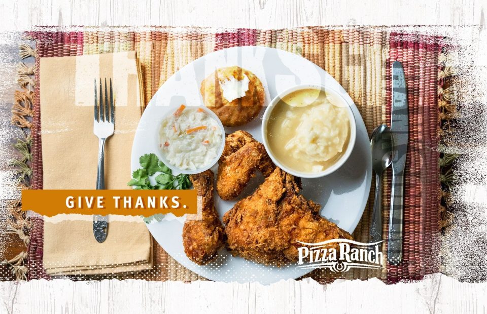 A plate with fried chicken, mashed potatoes, coleslaw, and a biscuit on a table with a woven placemat, with a fork on the left, a knife and spoon on the right, and a "Give Thanks" message overlay.