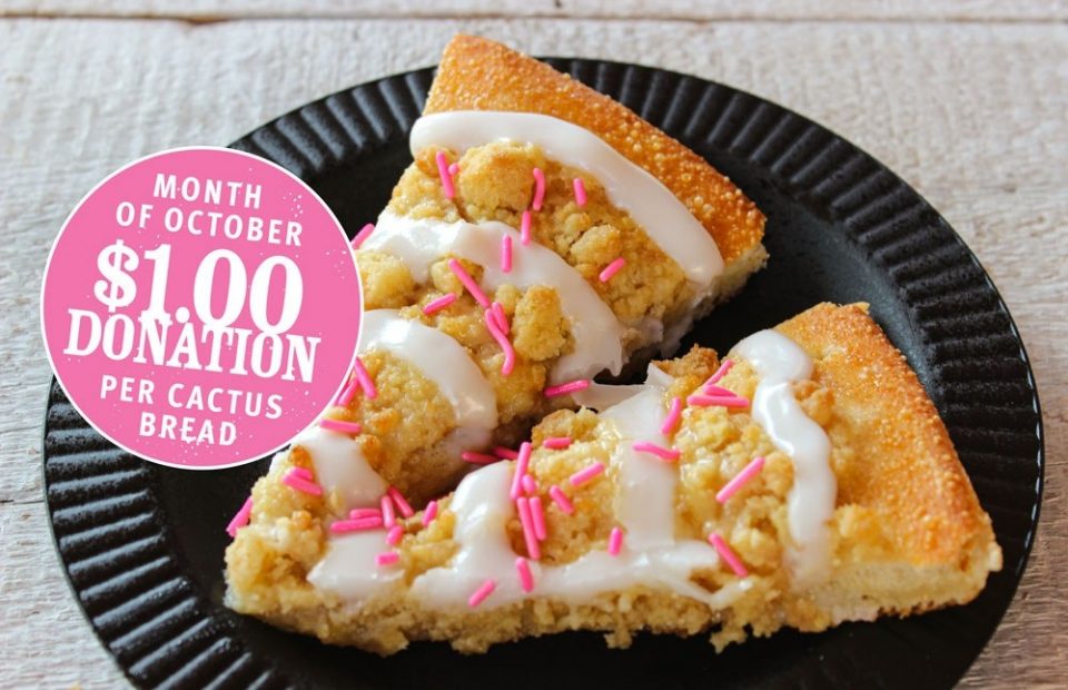 Slices of cactus bread with white icing and pink sprinkles on a black plate, with a pink circle showing a $1.00 donation per cactus bread for October.