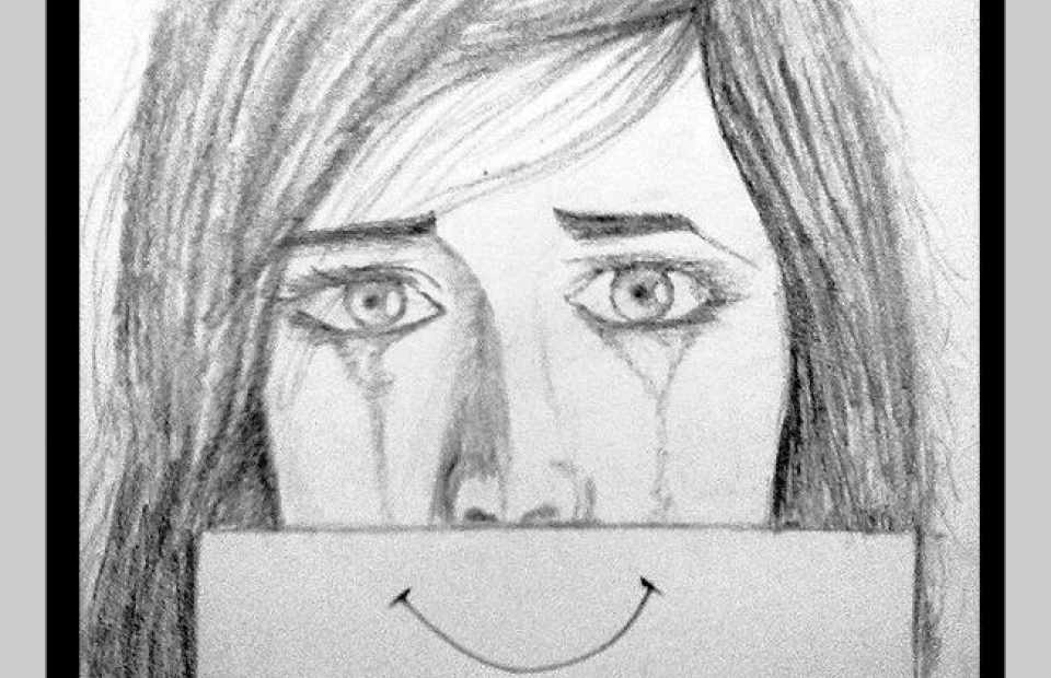 A woman with long hair holds a sign with a smiling face, but appears to be crying with tears running down her cheeks, conveying mixed emotions.