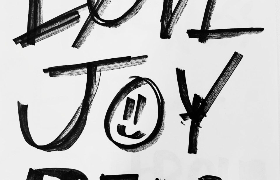 "Handwritten black brushstrokes spell out 'Love, Joy, Peace' on a white background with a smiling face drawn inside the 'O' in 'Joy'."