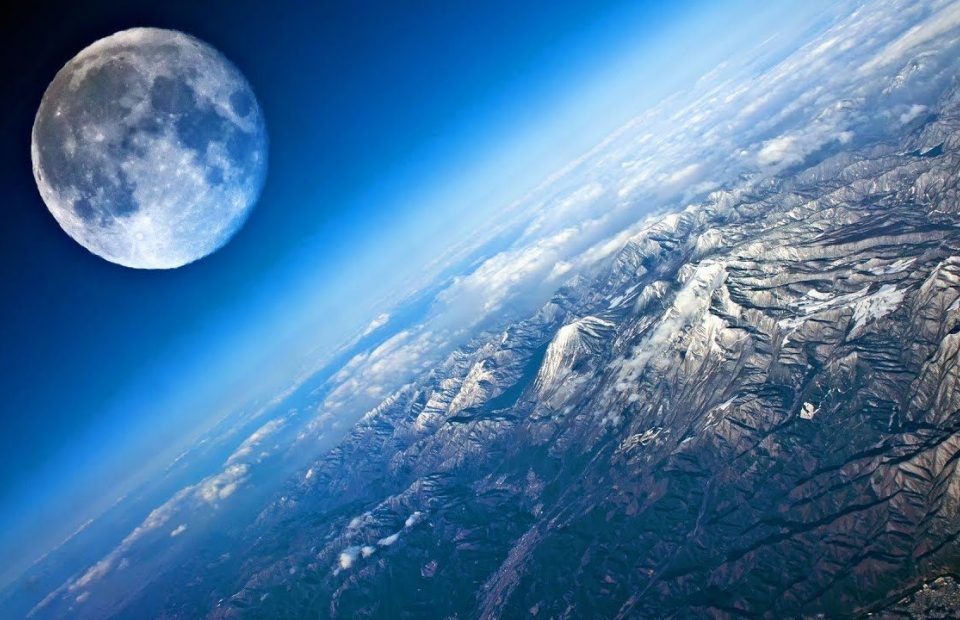 View of Earth's surface with mountains and snow, and the Moon in the sky above. The image is taken from space, showing atmosphere and clouds.
