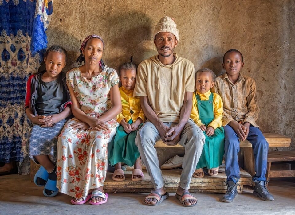 Kassa and Betehelm sit with their family in the home they rent in Azedebo. The family moved to Azedebo so their children would have an opportunity to attend school, as their permanent home is too far away for their children to walk each day safely. One of the student's education is paid for through the Hope Student Sponsorship program.