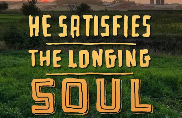 A sunset over a grassy field with farm buildings in the distance, overlaid with the quote, "He satisfies the longing soul" from Psalm 107:9, in bold, yellow-filled text.