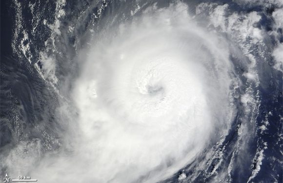 A satellite image of a large hurricane with a clear eye, swirling clouds, and heavy storm activity over the ocean.