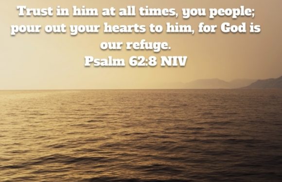 A peaceful ocean scene at sunset with mountains in the background, overlaid with a Bible verse from Psalm 62:8 NIV about trusting God.