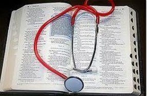 Open Bible with a red stethoscope forming a heart shape on top, placed on a white surface.