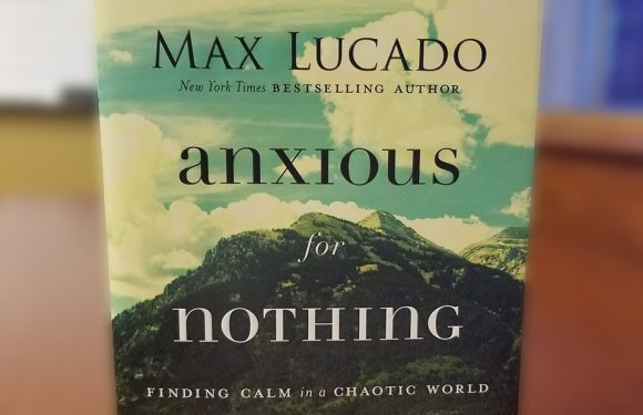 Cover of a book titled "Anxious for Nothing" by Max Lucado, featuring a green mountain landscape with a partly cloudy sky in the background.